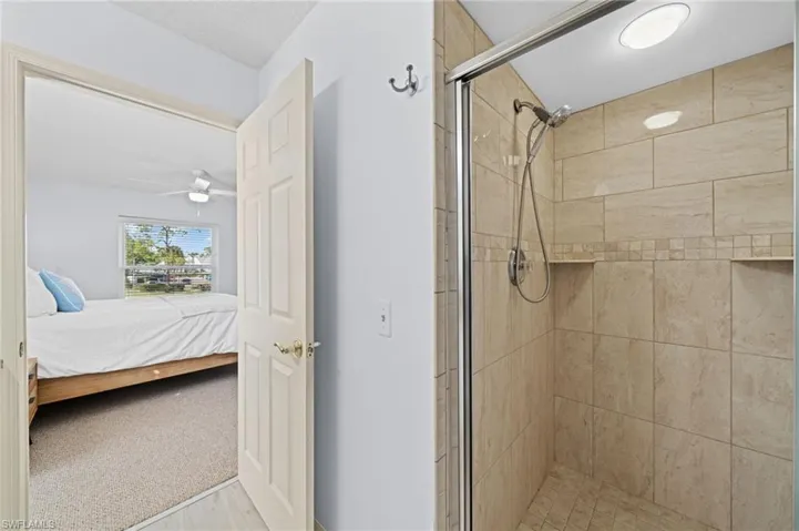 Full bathroom featuring light colored carpet, ensuite bath, a stall shower, and ceiling fan