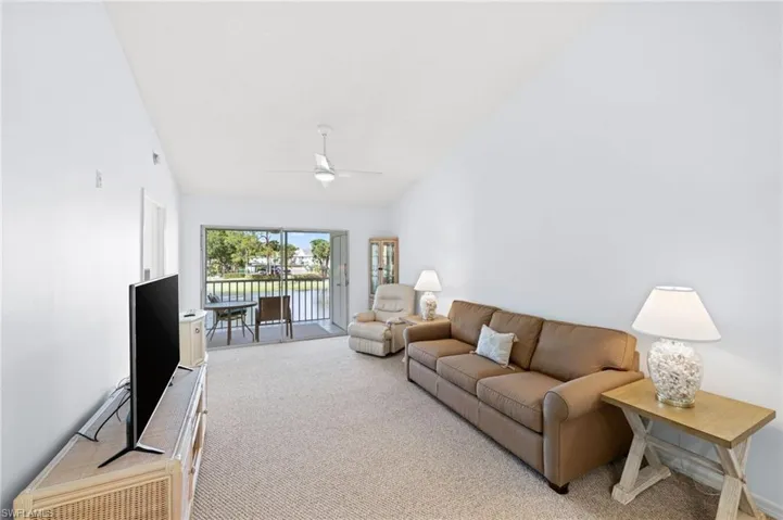 Living room with light carpet, vaulted ceiling, and ceiling fan