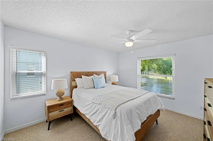 Carpeted bedroom with a ceiling fan and a textured ceiling