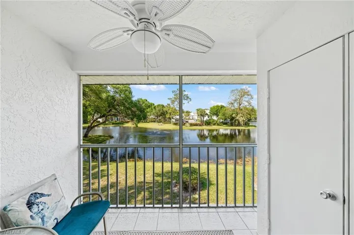 Unfurnished sunroom with a ceiling fan, a water view, and a balcony
