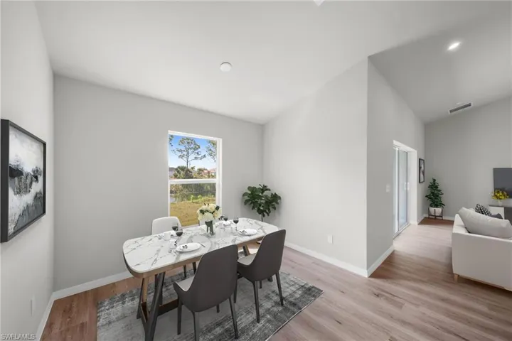 Dining area featuring vaulted ceiling, baseboards, and light wood finished floors