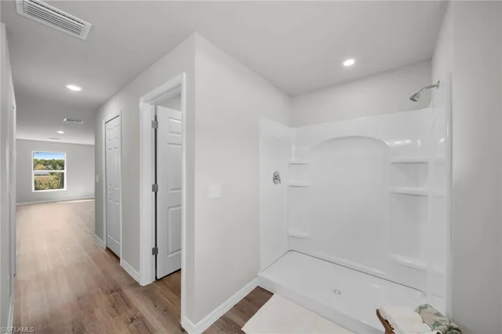 Full bathroom featuring visible vents, baseboards, recessed lighting, wood finished floors, and a shower