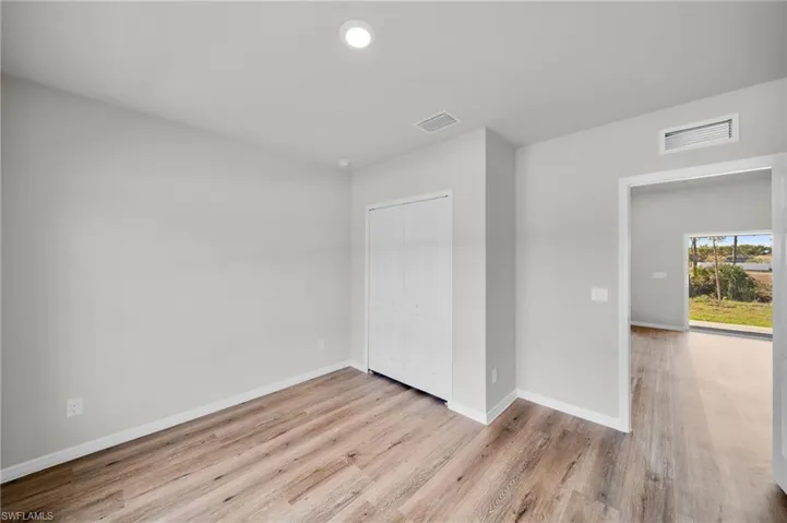 Unfurnished room featuring visible vents, baseboards, and wood finished floors