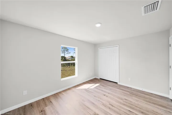 Unfurnished bedroom with light wood-style flooring, baseboards, visible vents, and a closet