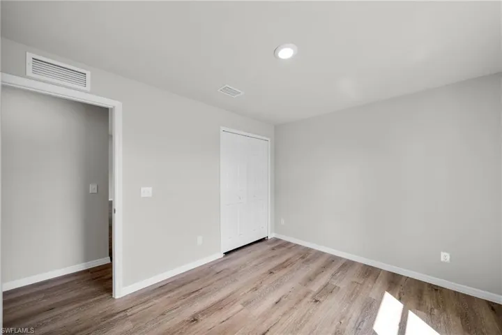 Unfurnished bedroom with visible vents, baseboards, a closet, and wood finished floors