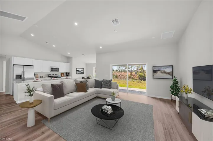 Living room with light wood-style flooring, recessed lighting, visible vents, and high vaulted ceiling
