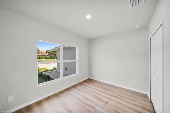 Empty room featuring light wood-type flooring, visible vents, baseboards, and recessed lighting