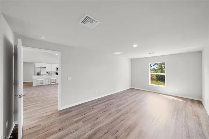 Spare room with light wood-type flooring, visible vents, and baseboards