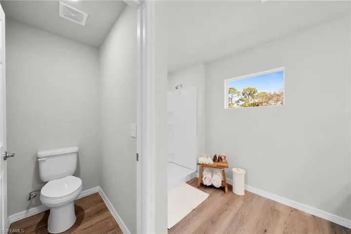 Bathroom featuring visible vents, baseboards, toilet, and wood finished floors