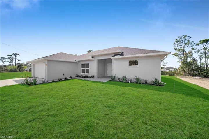 View of front of home featuring a front yard, roof with shingles, driveway, stucco siding, and a garage