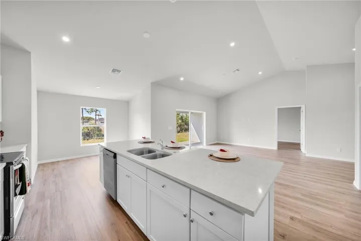 Kitchen featuring visible vents, a sink, white cabinetry, light wood-style floors, and appliances with stainless steel finishes