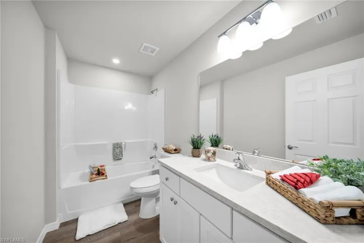 Full bathroom featuring visible vents, toilet, wood finished floors, bathing tub / shower combination, and vanity