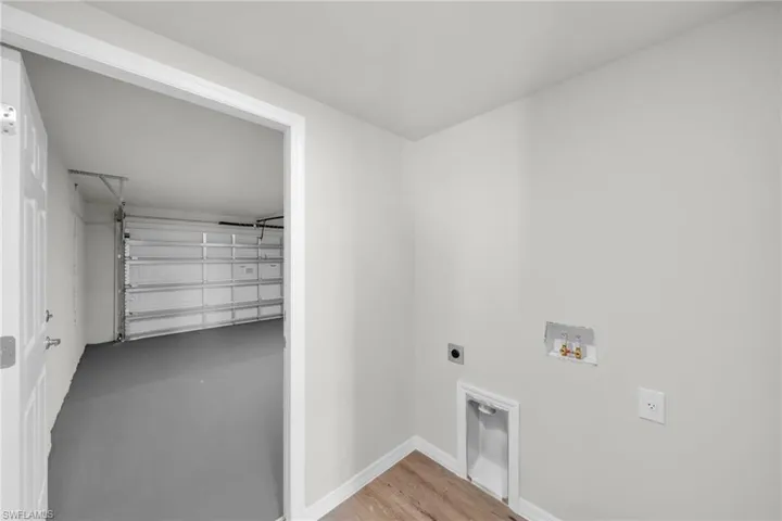 Laundry room with washer hookup, a garage, baseboards, hookup for an electric dryer, and laundry area