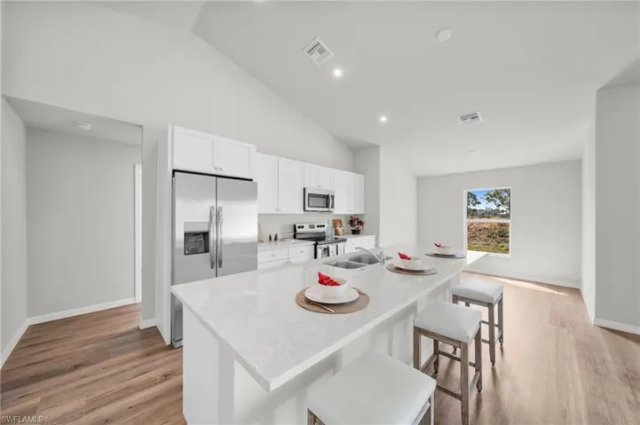 Kitchen featuring visible vents, light wood-style flooring, light countertops, appliances with stainless steel finishes, and white cabinetry