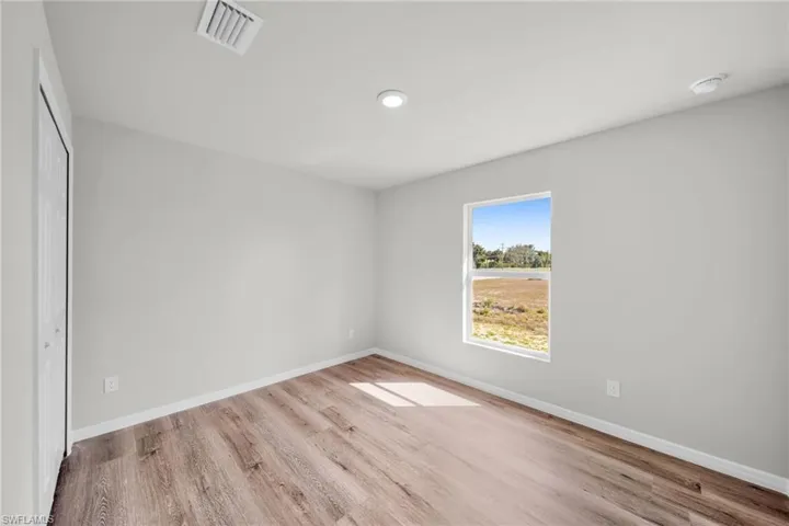 Empty room featuring visible vents, baseboards, and wood finished floors
