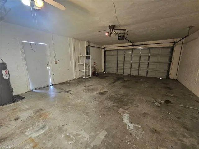Garage featuring water heater, a garage door opener, and ceiling fan