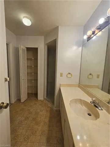 Full bathroom featuring vanity, tile patterned floors, a closet, a stall shower, and baseboards