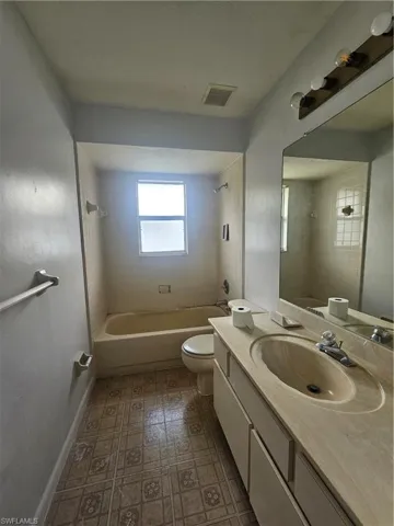 Full bath with toilet, washtub / shower combination, vanity, and baseboards