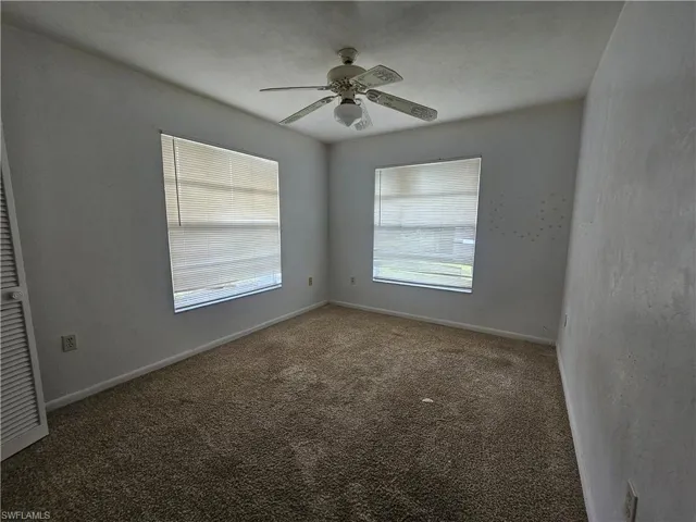 Empty room with carpet floors, a ceiling fan, and baseboards