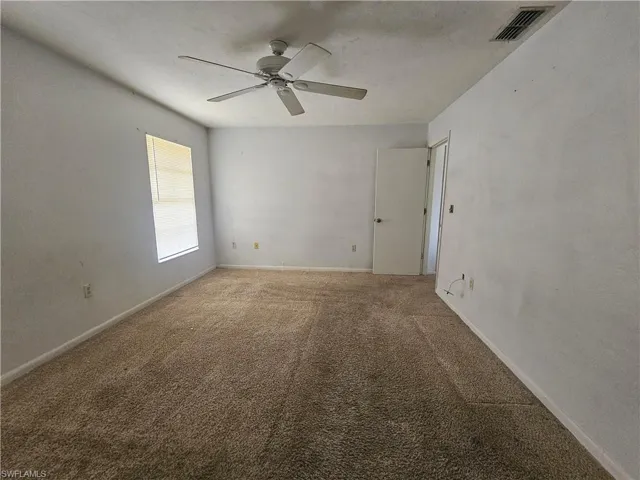 Empty room with light carpet, ceiling fan, and baseboards