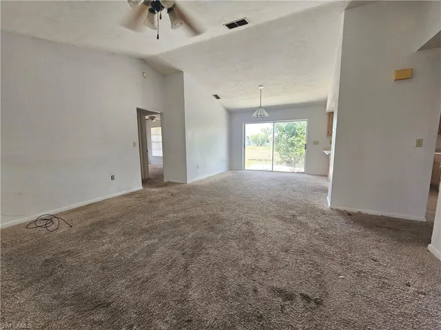 Spare room with ceiling fan, carpet flooring, lofted ceiling, and baseboards