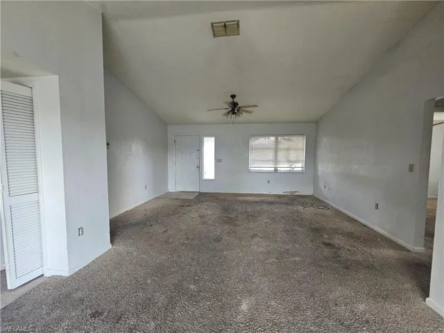 Unfurnished living room featuring vaulted ceiling, a ceiling fan, carpet, and baseboards