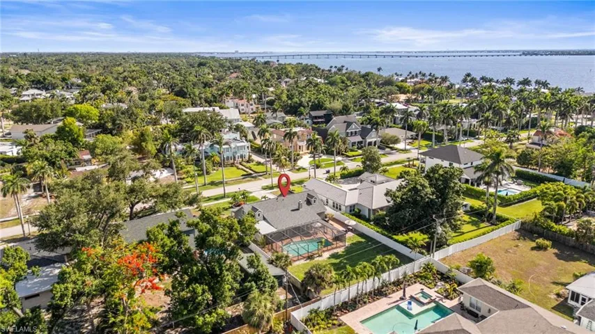 Aerial perspective of suburban area featuring a pool and a nearby body of water