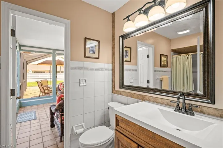 Bathroom featuring tile walls, toilet, vanity, tile patterned flooring, and wainscoting