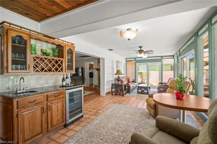 Indoor wet bar featuring wine cooler, light tile patterned floors, tasteful backsplash, and a ceiling fan