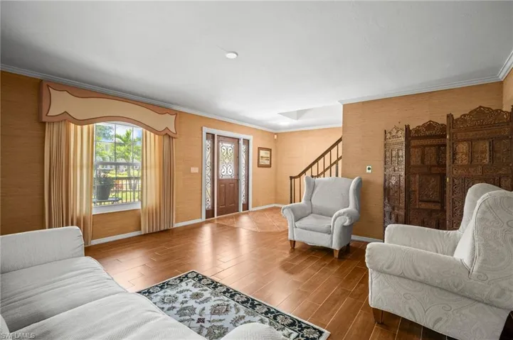 Living area with ornamental molding, stairway.