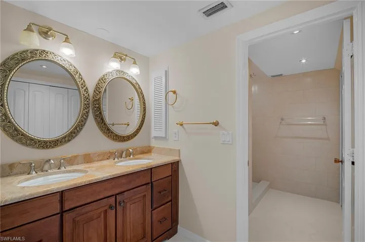 Full bath with double vanity and tiled shower