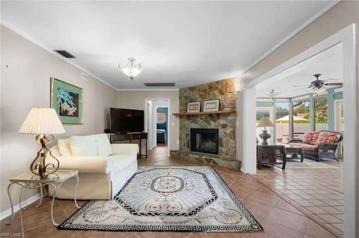 Living area with crown molding, tile patterned flooring, a fireplace, ceiling fan, and baseboards