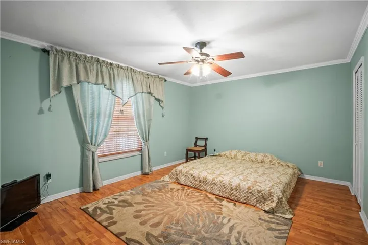 Bedroom with wood finished floors, ornamental molding, a closet, and ceiling fan