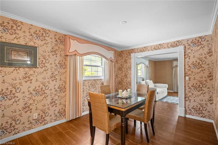 Dining room featuring ornamental molding, and wallpapered walls