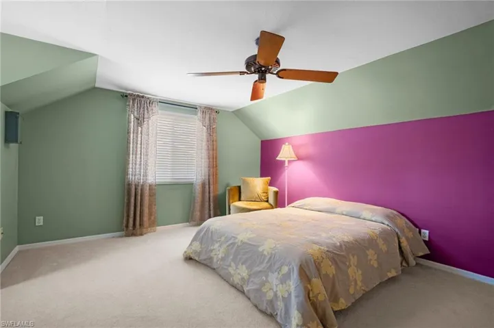 Bedroom featuring lofted ceiling, carpet floors, baseboards, and a ceiling fan