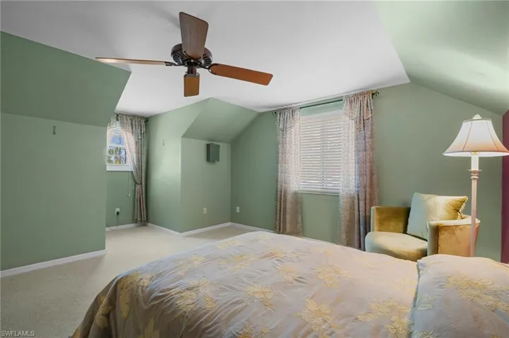 Bedroom with vaulted ceiling, baseboards, carpet floors, and a ceiling fan