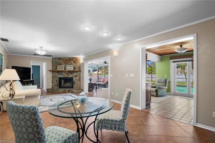 Tiled dining space featuring ornamental molding, plenty of natural light, a stone fireplace, baseboards, and a ceiling fan