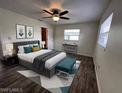Spacious bedroom featuring wood-finish flooring, light-colored walls, and a ceiling fan with integrated lighting