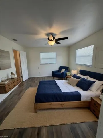 Spacious room featuring wood-finish flooring, a ceiling fan with integrated lighting, and two windows providing natural light