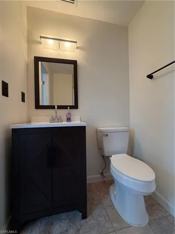 Vanity with dark wood-finish cabinetry, white countertop, and rectangular mirror