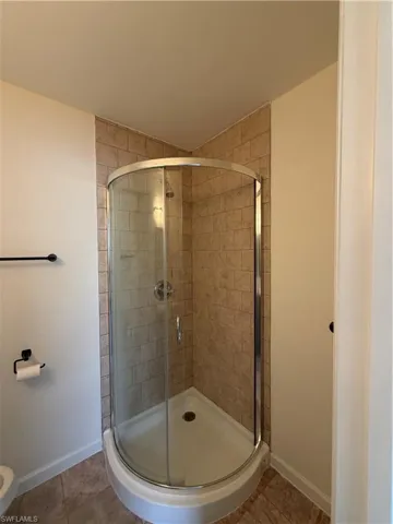 Corner shower enclosure featuring clear glass and a tiled surround