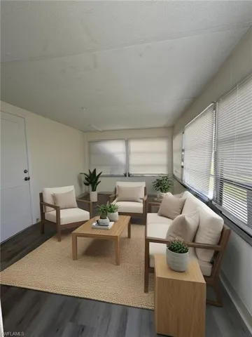 Enclosed sunroom featuring a white door, plank flooring, and multiple windows with blinds