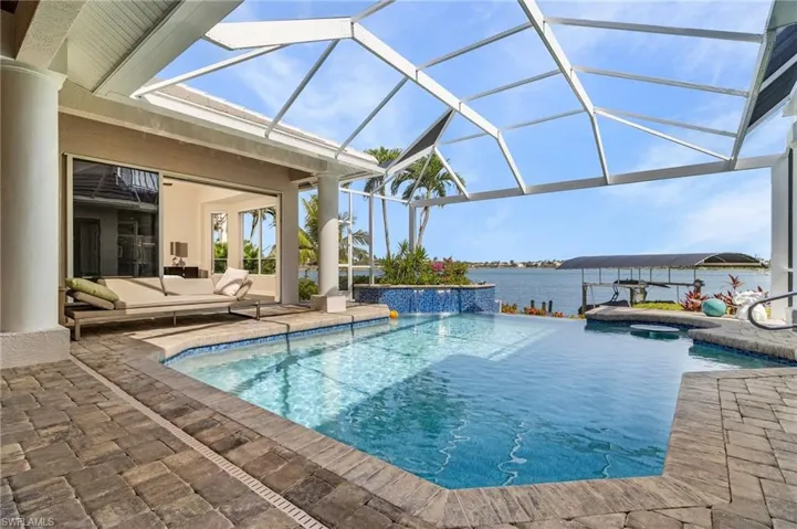Outdoor pool with waterfall, a patio area, outdoor lounge area, a water view