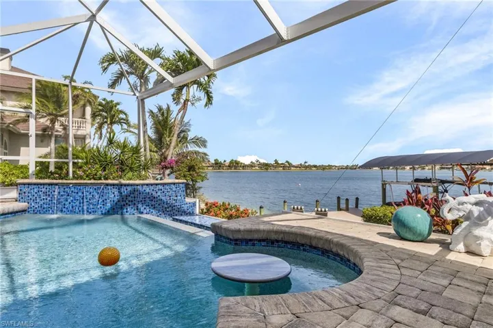 Southern exposure view lookin out to lake with swimming pool and bench seat with table in pool