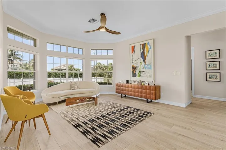 Living room featuring a ceiling fan, wood finished floors, and ornamental molding