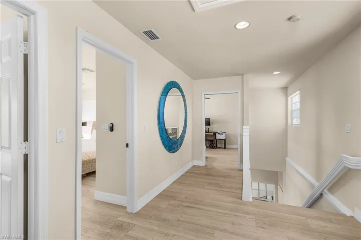 Corridor with an upstairs landing, light wood-type flooring, and recessed lighting