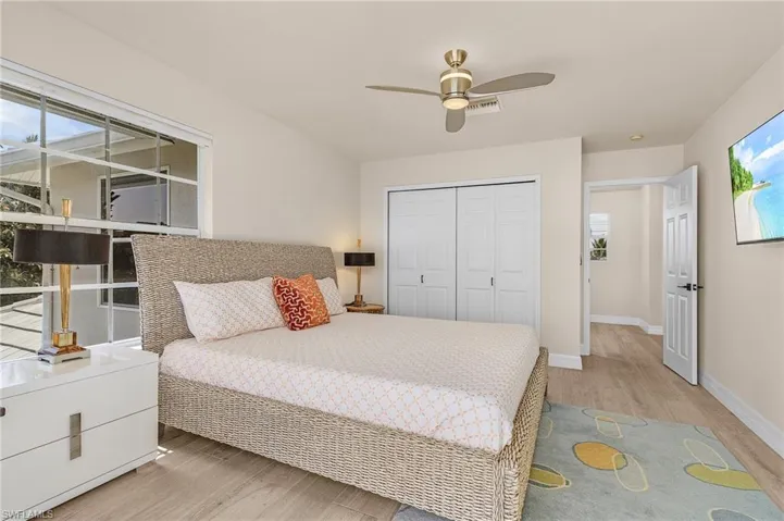 Bedroom with light wood finished floors, a closet, multiple windows, and ceiling fan