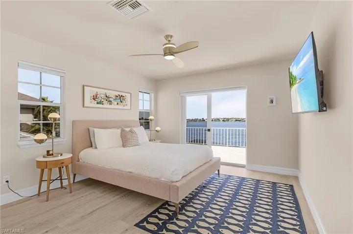 Bedroom featuring access to exterior, light wood-type flooring, and multiple windows