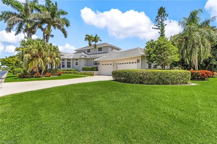 View of front of house featuring a garage, driveway, a front lawn, and stucco siding