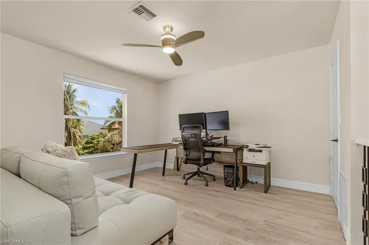 Office area with a ceiling fan and light wood-style floors